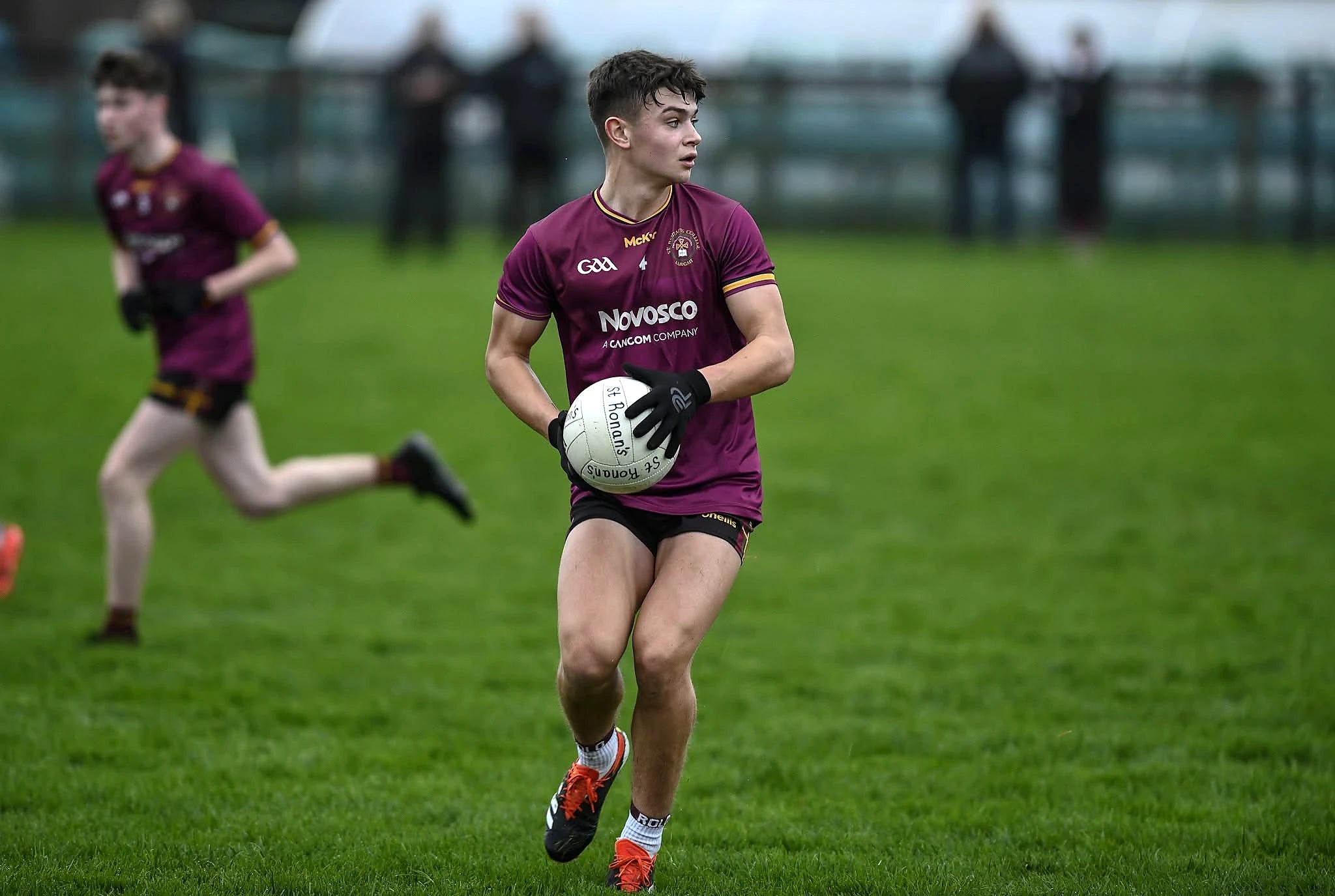 Gaelic footballer carrying the ball while wearing PalmPro strapless gloves